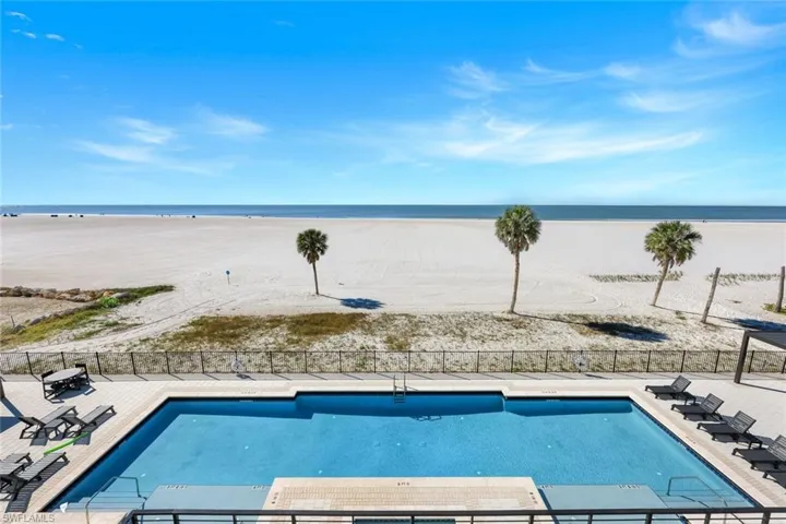 Community pool featuring a patio area and view of water and beach
