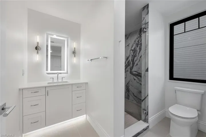 Bathroom featuring vanity, a marble finish shower, and light tile patterned floors
