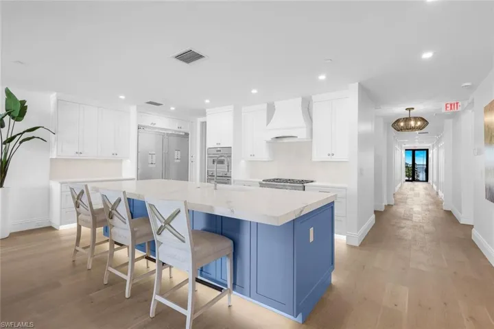 Kitchen with two tone cabinetry, an island with sink, a kitchen breakfast bar, recessed lighting, and built in refrigerator