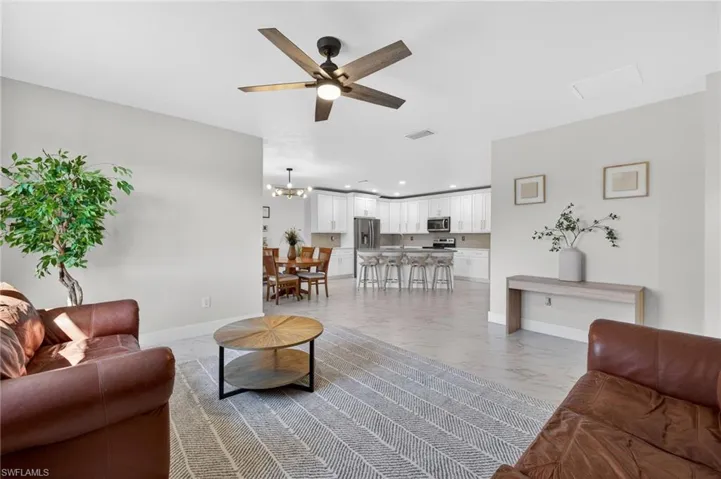 Living room with light marble finish flooring, ceiling fan, and hanging lights