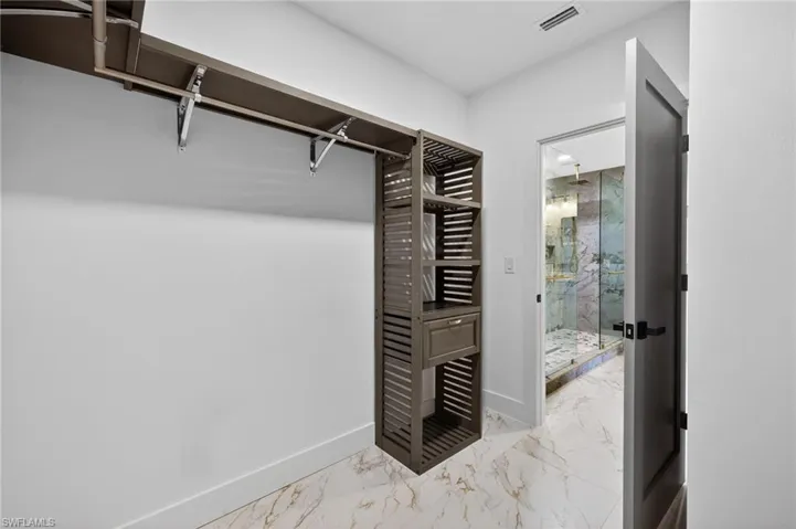 Walk in closet featuring light marble finish flooring