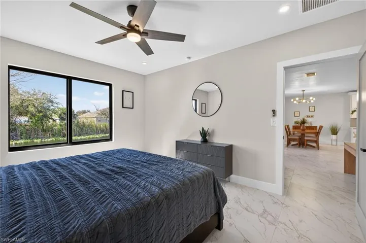 Bedroom featuring light marble finish flooring, ceiling fan, and hanging lights