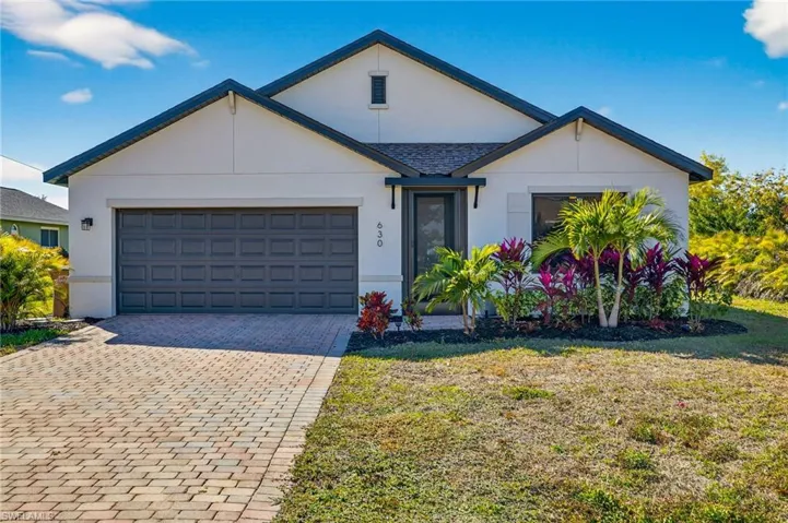 Ranch-style house featuring stucco siding, driveway, a front yard, and a garage