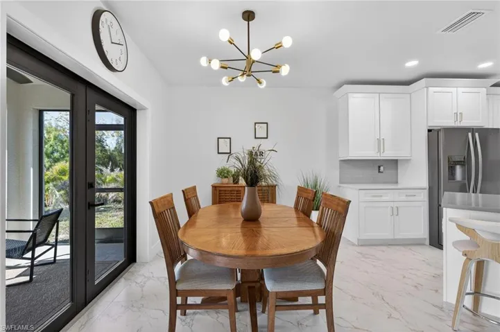 Dining room with suspended lighting, french doors, and light marble finish flooring