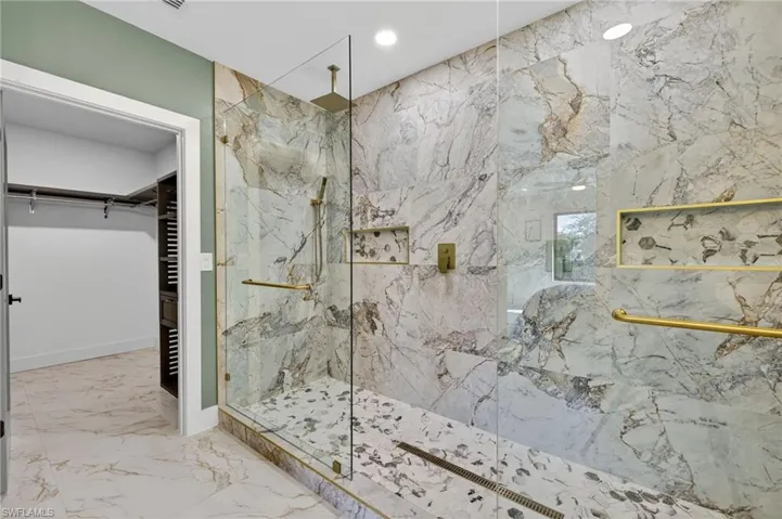 Bathroom featuring a spacious closet, a marble finish shower, light marble finish flooring, and recessed lighting