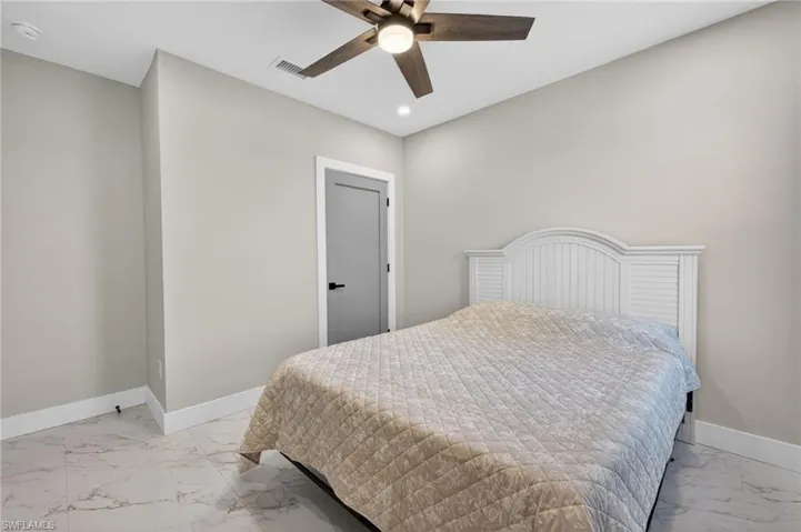 Bedroom featuring ceiling fan, light marble finish floors, and recessed lighting