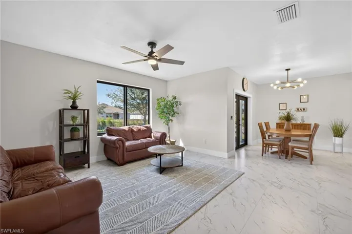 Living area featuring light marble finish flooring, a ceiling fan, and a chandelier