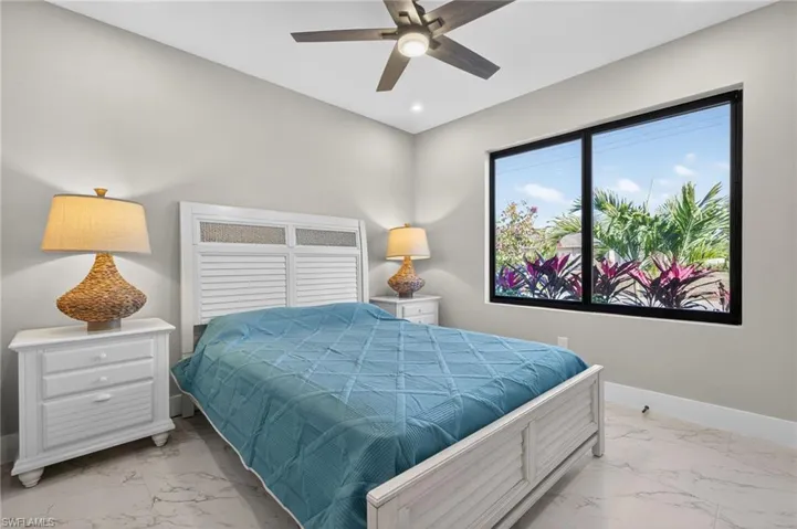 Bedroom with ceiling fan and light marble finish floors