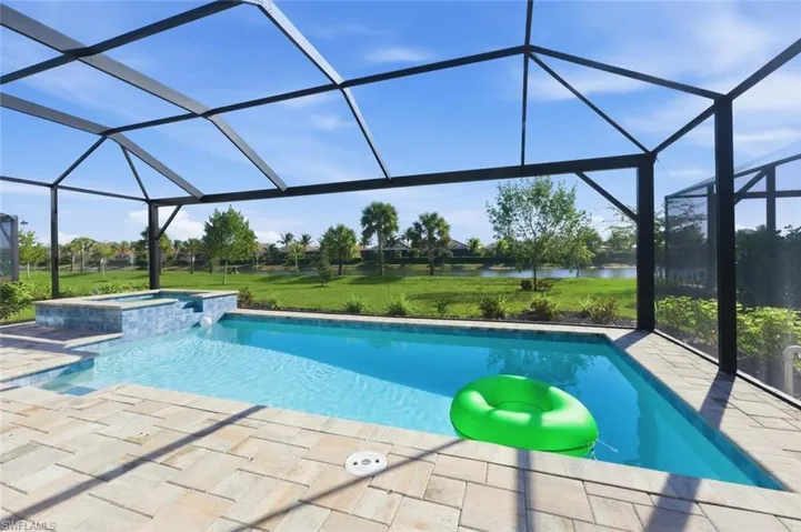 Integrated pool / hot tub with a sunroom, a lawn, and glass enclosure
