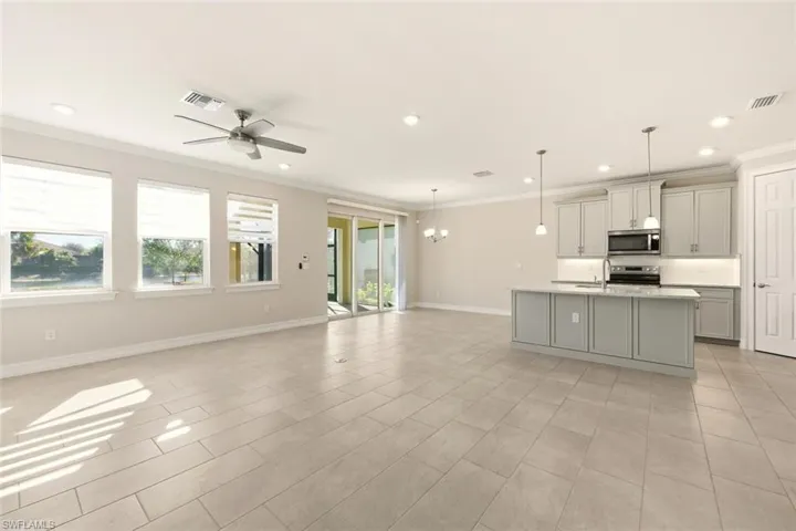 Kitchen with a chandelier, open floor plan, gray cabinetry, stainless steel appliances, and ornamental molding