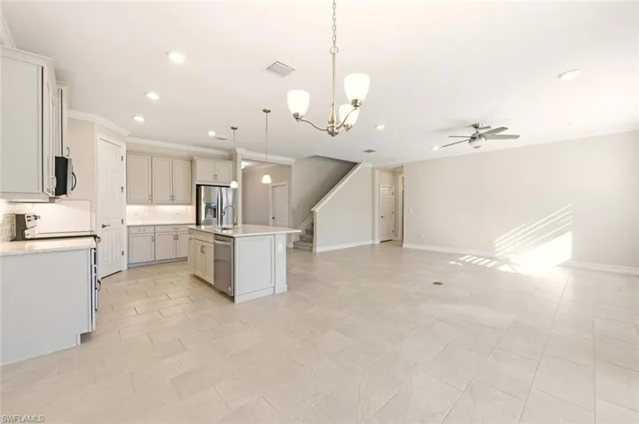 Kitchen with a chandelier, a kitchen island with sink, stainless steel appliances, open floor plan, and decorative backsplash