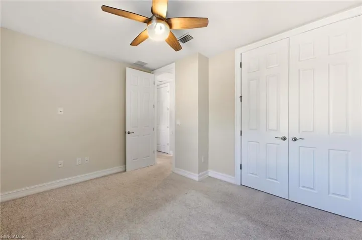 Unfurnished bedroom featuring light carpet, a closet, and ceiling fan
