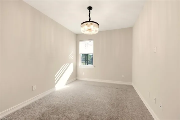Spare room featuring a chandelier and light colored carpet