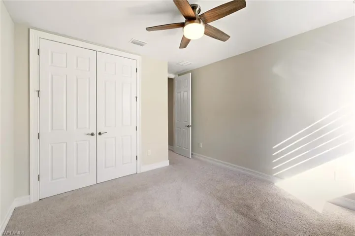 Unfurnished bedroom featuring carpet flooring, a closet, and a ceiling fan