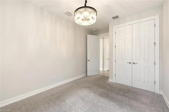 Unfurnished bedroom with carpet flooring, suspended lighting, and a closet