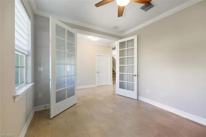 Empty room featuring french doors, a ceiling fan, and ornamental molding