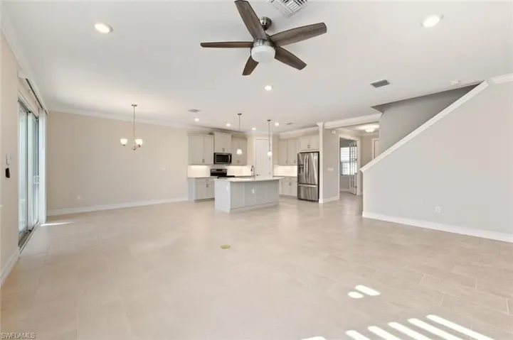 Unfurnished living room featuring a ceiling fan, a chandelier, and ornamental molding