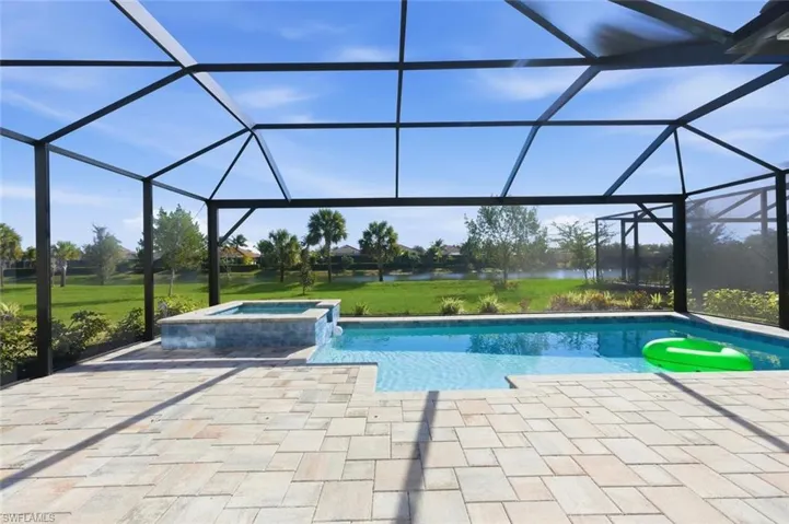 Integrated pool / spa with a sunroom, a lawn, glass enclosure, and a patio area
