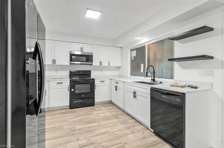 Kitchen with black appliances, open shelves, white cabinetry, and light wood-type flooring