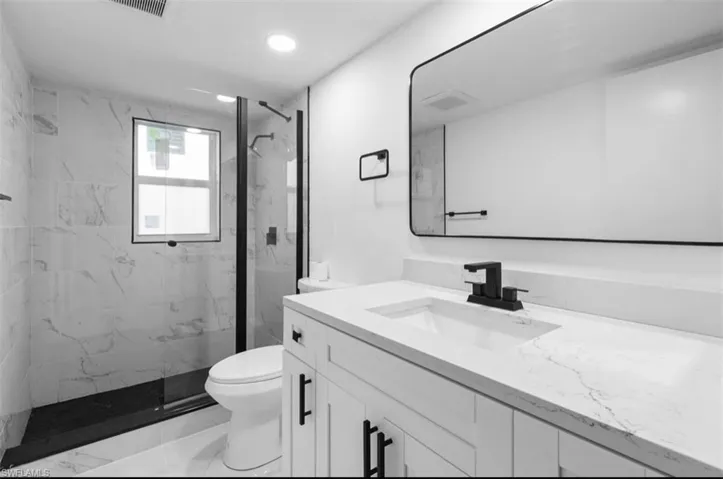 Full bath with vanity, a marble finish shower, and recessed lighting