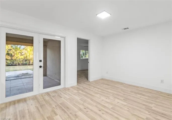 Unfurnished room featuring light wood-style flooring and french doors