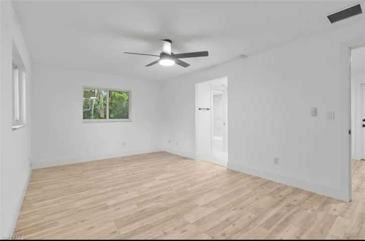 Unfurnished bedroom featuring ceiling fan, light wood finished floors, and ensuite bath