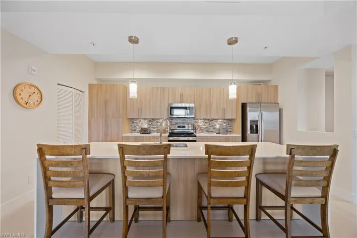 Kitchen with tasteful backsplash, light countertops, a sink, stainless steel appliances, and light brown cabinets