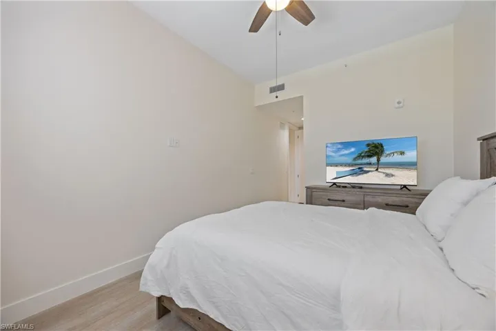 Bedroom with light wood-type flooring, baseboards, a ceiling fan, and visible vents