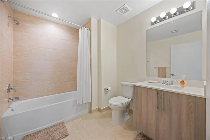 Bathroom with shower / bath combo, visible vents, toilet, and vanity