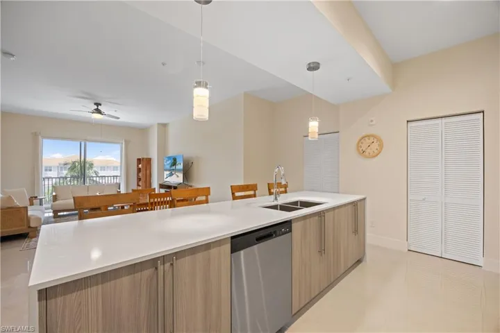 Kitchen featuring open floor plan, light countertops, a ceiling fan, dishwasher, and a sink