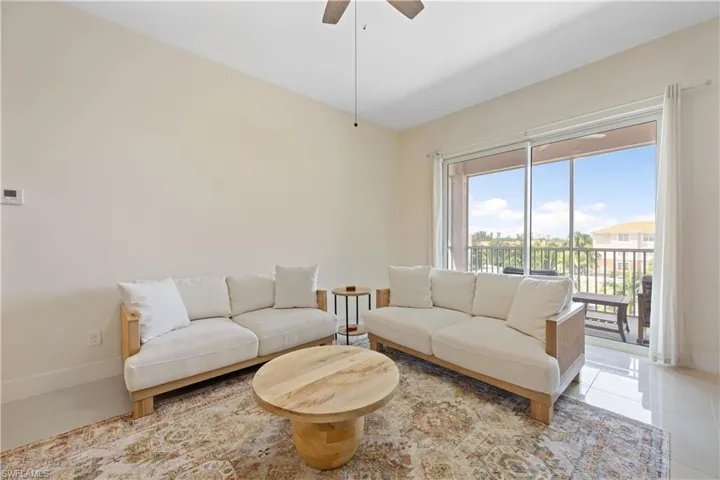 Living room with light tile patterned floors, ceiling fan, lofted ceiling, and baseboards