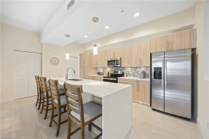 Kitchen with decorative backsplash, light brown cabinets, a sink, and appliances with stainless steel finishes