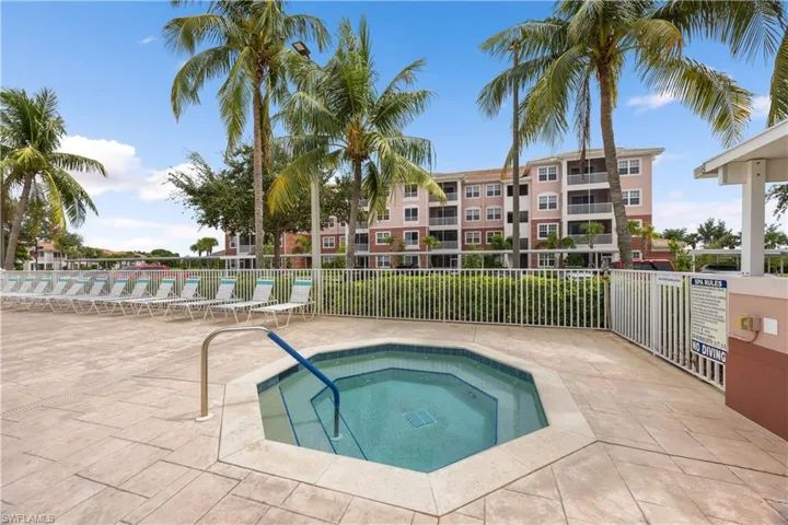 View of swimming pool featuring a patio, fence, and a hot tub