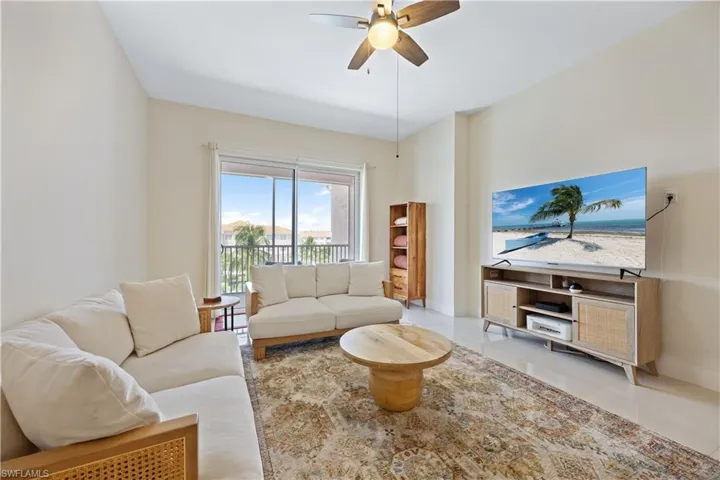 Tiled living room with ceiling fan and baseboards