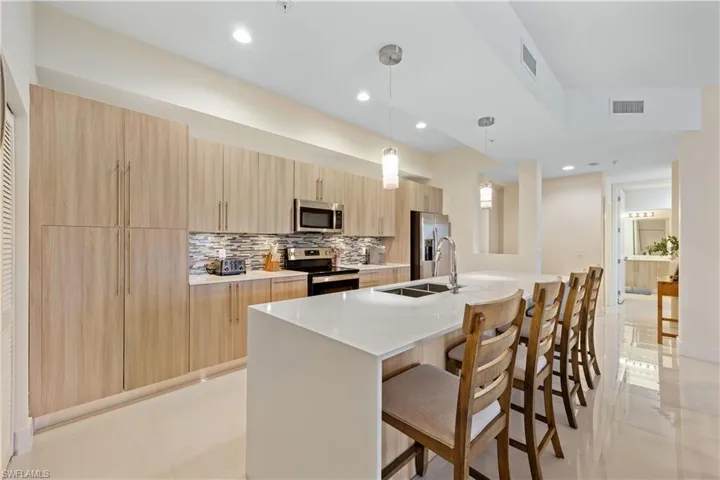 Kitchen featuring light brown cabinetry, appliances with stainless steel finishes, a sink, and modern cabinets