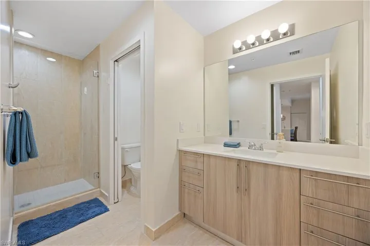 Full bath with a shower stall, vanity, visible vents, toilet, and baseboards