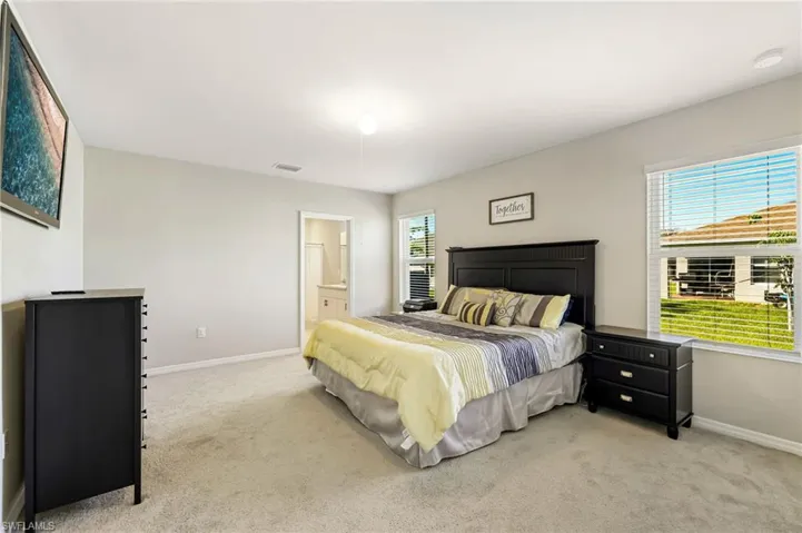 Bedroom with ensuite bath and light colored carpet