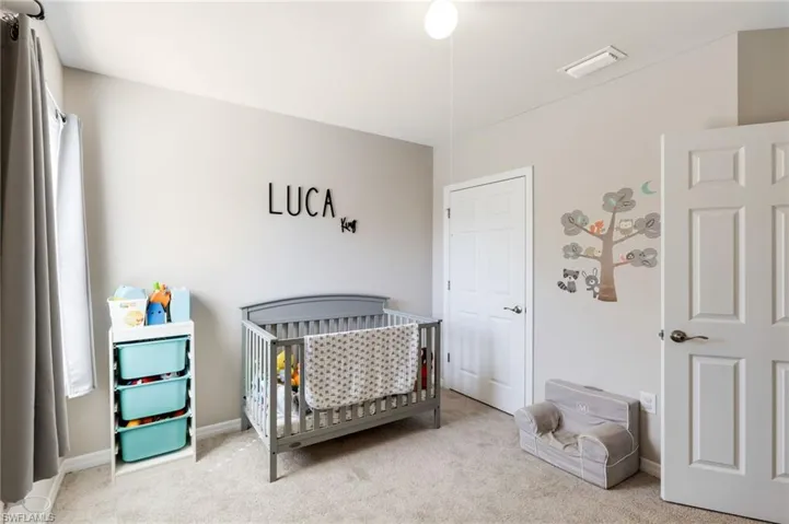 Carpeted bedroom featuring a crib