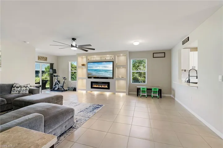 Living room featuring plenty of natural light, ceiling fan, light tile patterned floors, and sink
