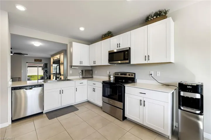 Kitchen featuring appliances with stainless steel finishes, ceiling fan, sink, white cabinets, and light tile patterned flooring