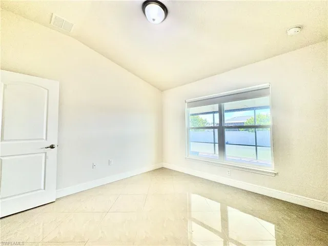 Unfurnished room featuring light tile patterned flooring and vaulted ceiling