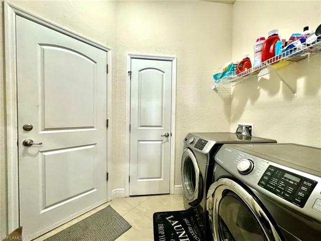 Clothes washing area with light tile patterned flooring and washing machine and clothes dryer
