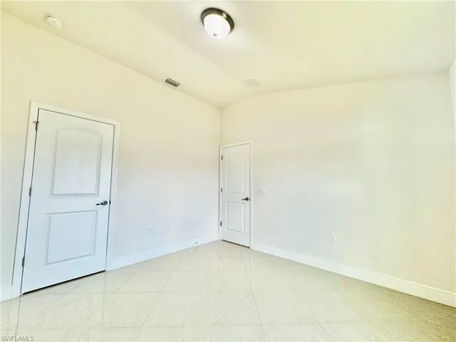 Tiled empty room featuring lofted ceiling