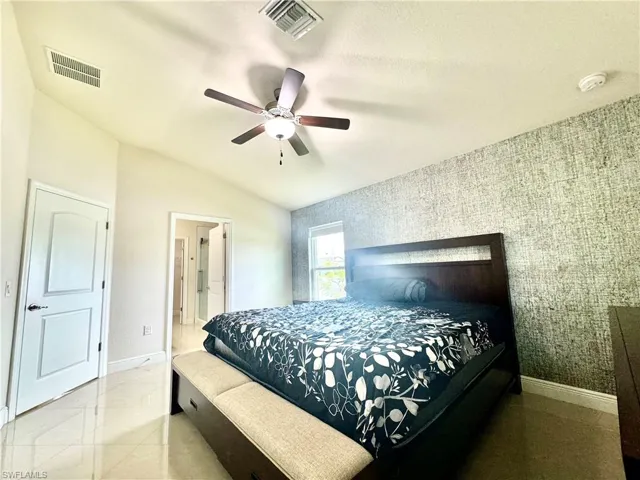 Bedroom with ceiling fan, light tile patterned floors, and vaulted ceiling