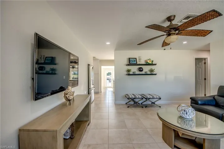 Living area with a ceiling fan, light tile patterned floors, and recessed lighting