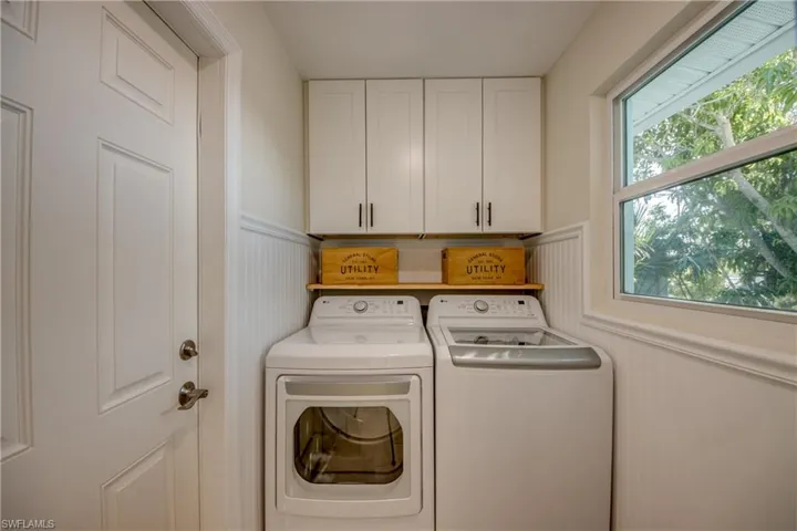 Laundry room featuring washer and clothes dryer, cabinet space, and wainscoting