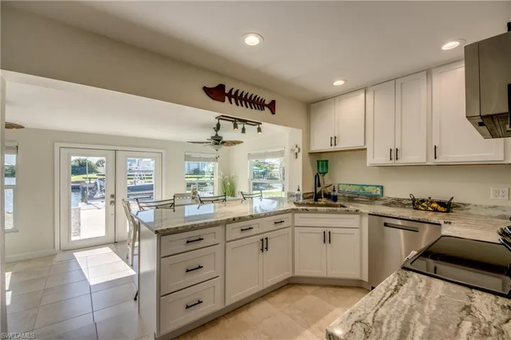 Kitchen featuring french doors, a peninsula, white cabinetry, light stone counters, and recessed lighting