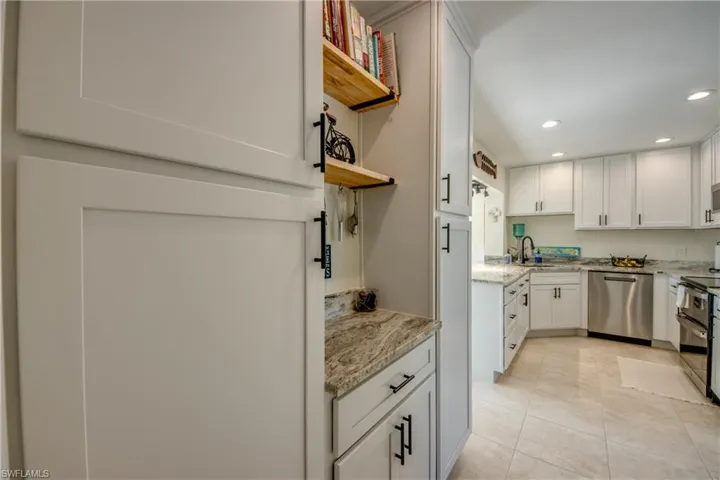 Kitchen featuring dishwasher, recessed lighting, light stone countertops, open shelves, and white cabinets