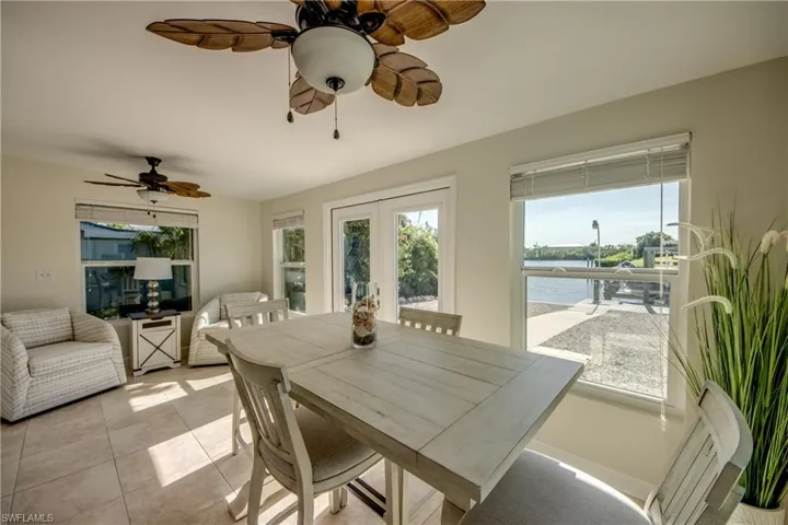 Dining area featuring a water view, a ceiling fan, french doors, and light tile patterned floors