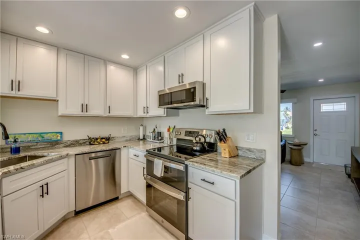 Kitchen featuring stainless steel appliances, white cabinetry, light tile patterned floors, recessed lighting, and light stone counters
